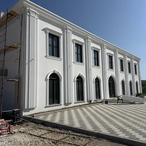 Fasadë neoklasike me pilastra të kaneluara, korniza dritaresh dhe harqe